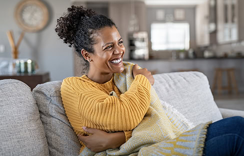 A woman appears comfortable on her couch at home.